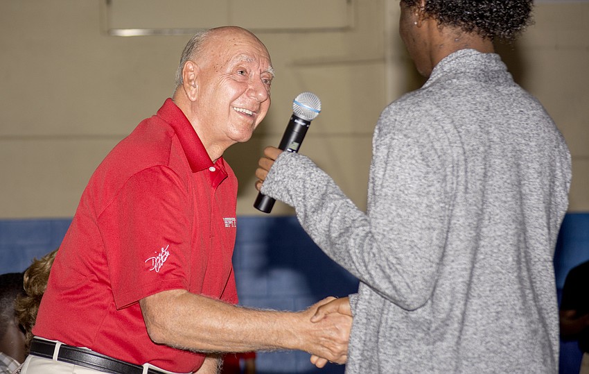Vitale shakes hands with scholarship recipient Hassan Hogan.
