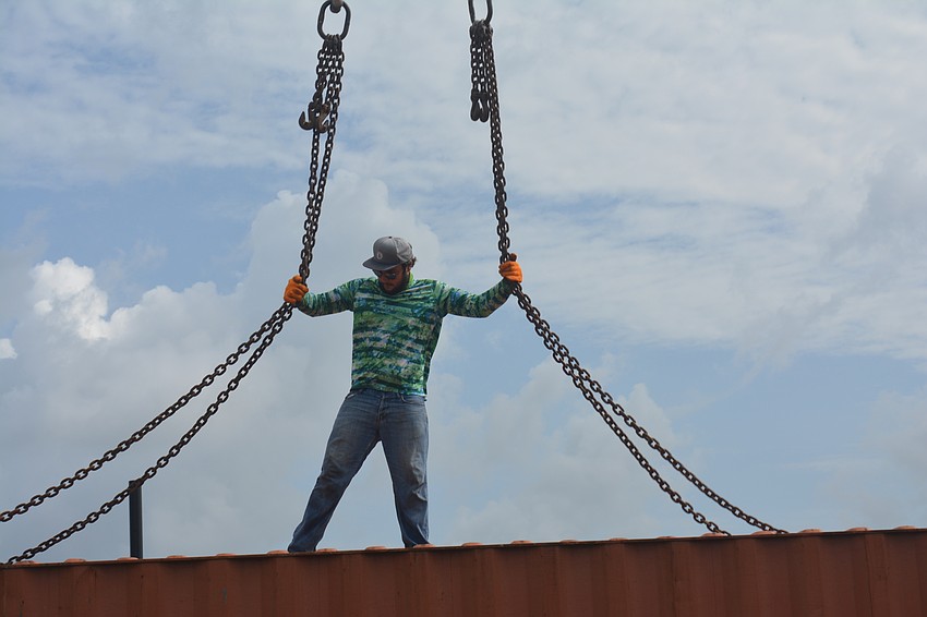 Skylar Bragg makes sure all the crane cables are connected to the crate.
