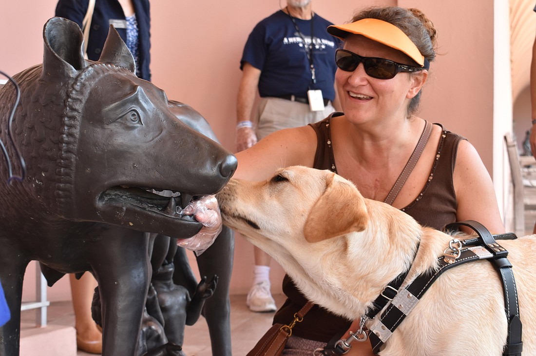 Allison Geske, who is visually impaired, laughs as her guide dog, Cessna, licks the statue of the Capitoline Wolf with Romulus and Remus in the museum courtyard.
