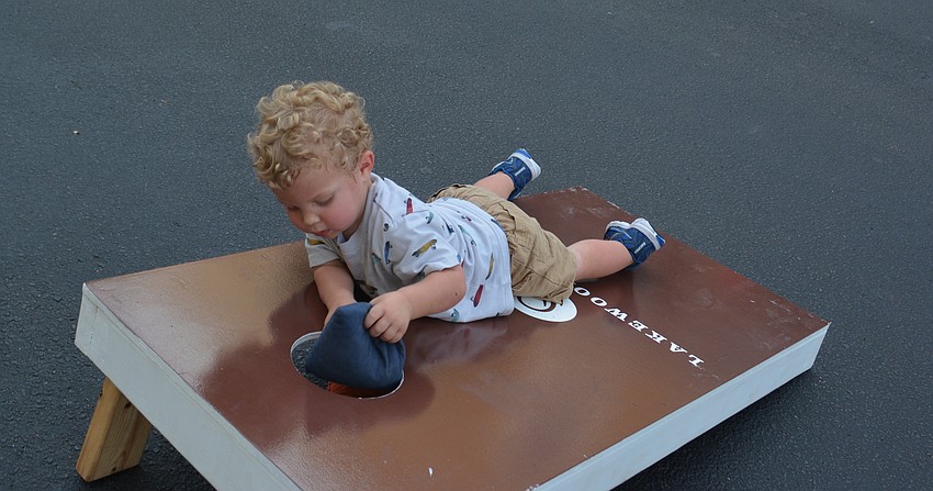 Lakewood Ranch's Jackson McIntyre, 2, discovers the best way to play Cornhole at Music on Main.