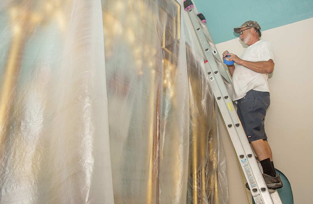 Steve Wernet secures a plastic covering over an alter reredos at the Church of the Redeemer on Sept. 7.