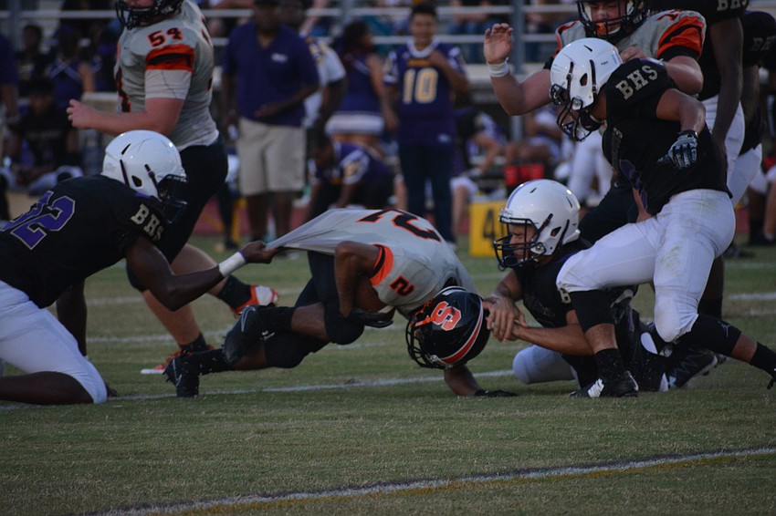 Sarasota's Tommie Battie IV gets dragged to the turf by Booker defenders.
