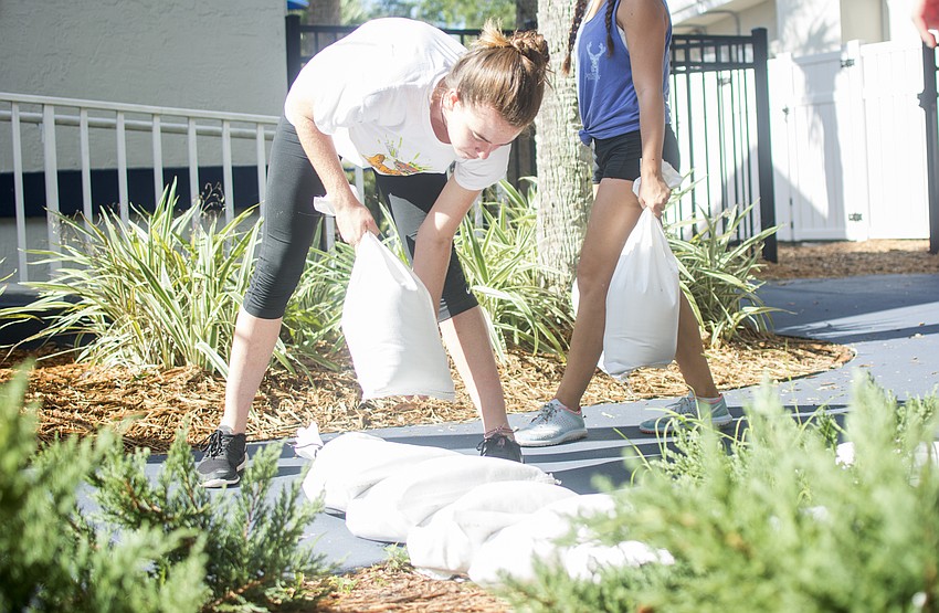 Adelaide Mahler lays sandbags across an entrance at Out-of-Door Academy's lower school campus on Sept. 8.