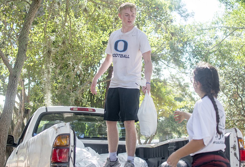Dylan Dennehy passes a sandbag to Haley Carney.