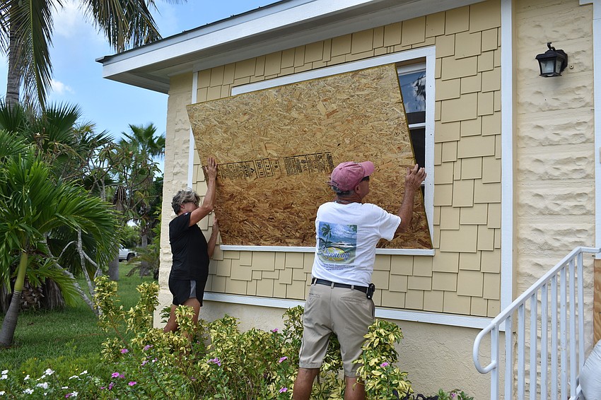 Karen and Brian Feeney board up their front window before evacuating Longboat Key.
