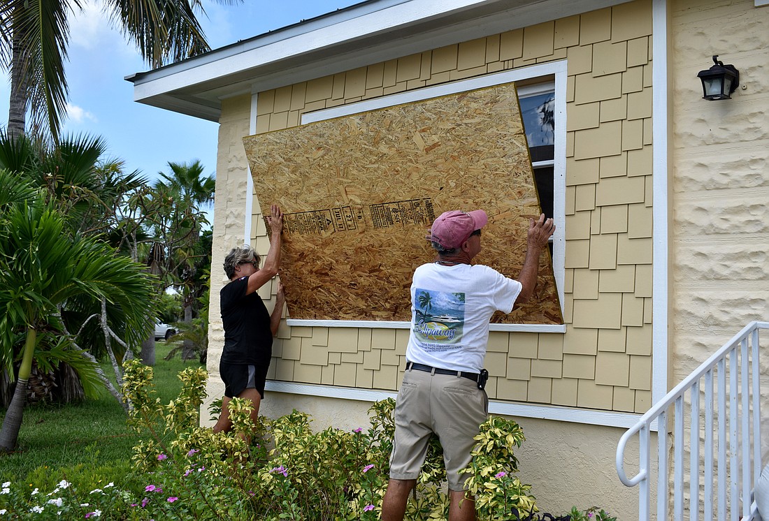 Karen and Brian Feeney board up their front window before evacuating Longboat Key on Sept. 8.