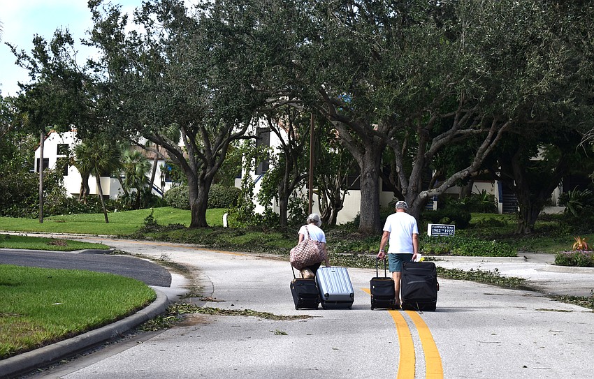 Pat and Tony Crincoli wheel their suitcases to their Bay Isles home. Residents of Bay Isles were not able to drive through the neighborhood due to fallen trees.  Photo by Katie Johns