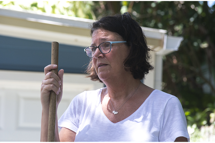 Lisa Dodds rakes fallen leaves and branches from her driveway of her north Siesta Key home.
