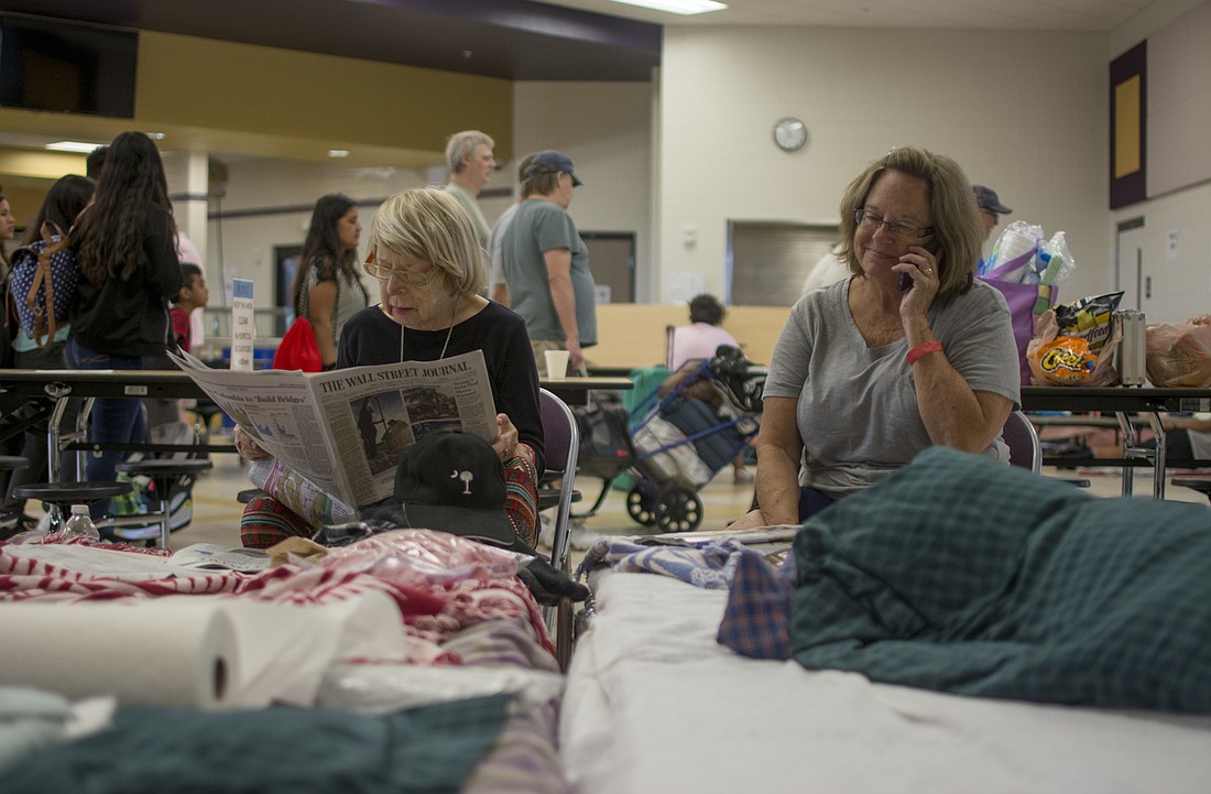 Larissa Green reads the Wall Street Journal while her daughter, Ann Green West, talks on the phone Saturday at Booker High School. The pair arrived with Howard Green on Friday night.
