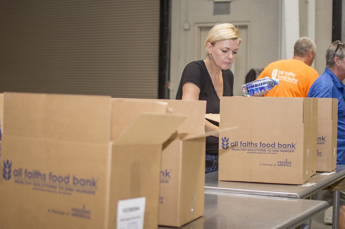 Darya Fedotova packs one of more than 22,000 disaster relief food boxes for All Faiths Food Banks emergency food distribution.