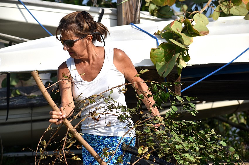Lisa Barzel removes tree branches from stored boats.