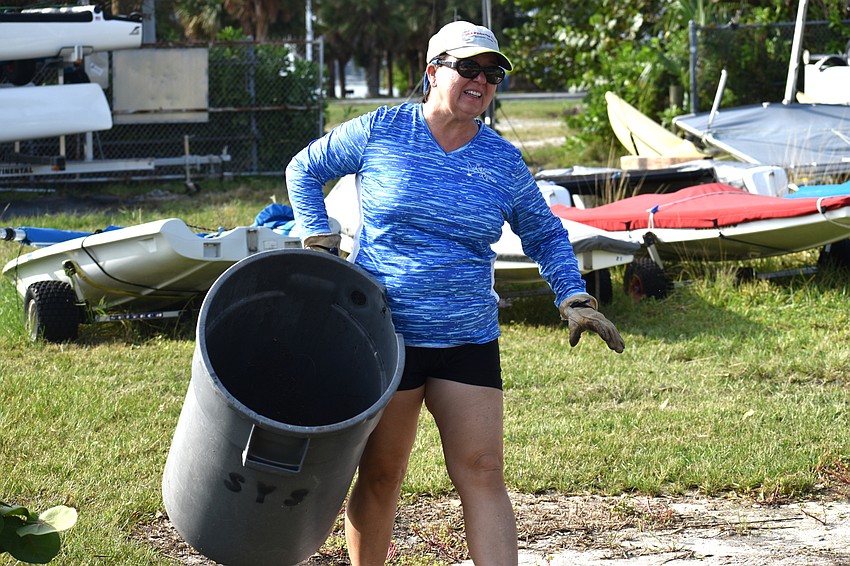 Judy Hodgson moves a garbage can back in place at the Sarasota Sailing Squadron.