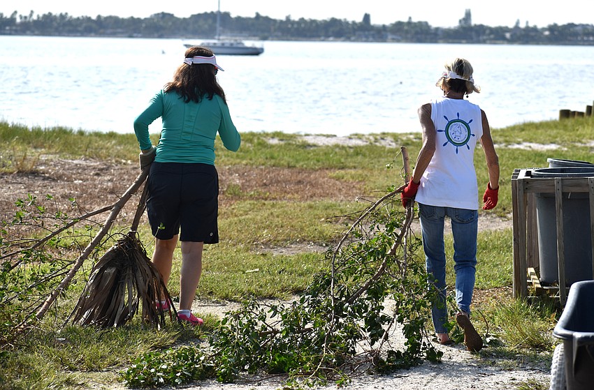 Linda Leader and Rosemary McMullen carry tree debris while helping clean up the Sarasota Sailing Squadron.