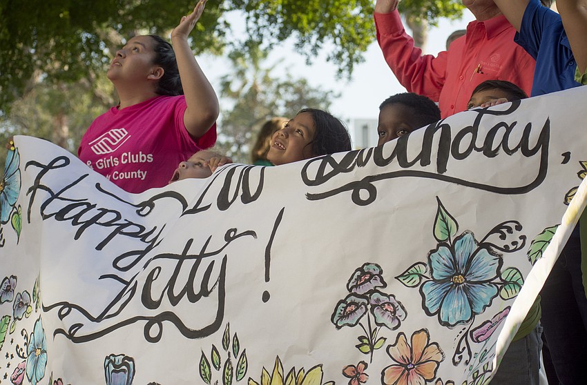 Boys and Girls Club member Vanessa helps hold a banner wishing Betty Schoenbaum a happy birthday.
