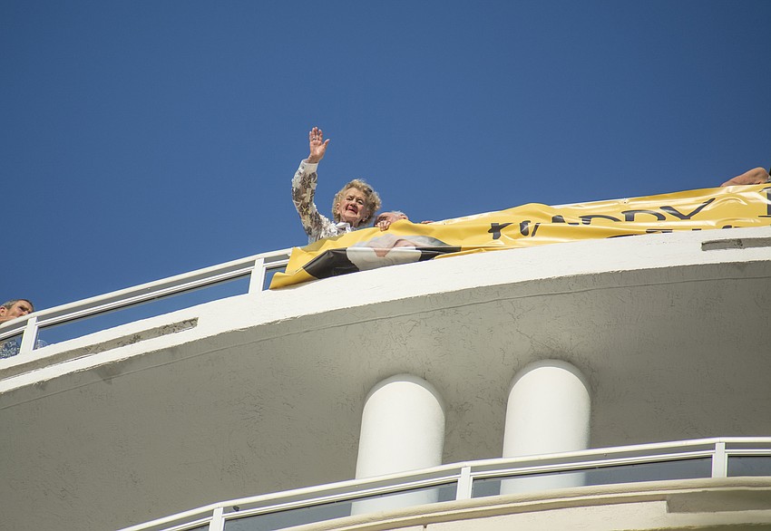 Betty Schoenbaum waves at well wishers from her balcony during her birthday parade.