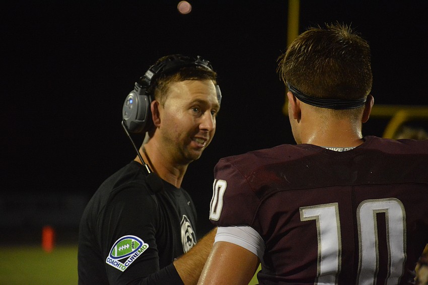 Pirates offensive coordinator Eric Sanders gives junior quarterback Bryan Gagg instructions.