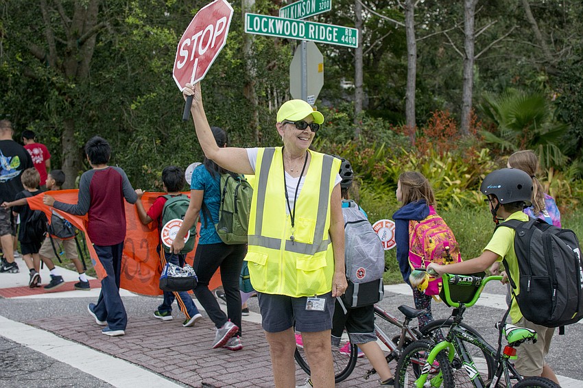 Ethel Heroux directs traffic as Wilkinson students walk behind her.