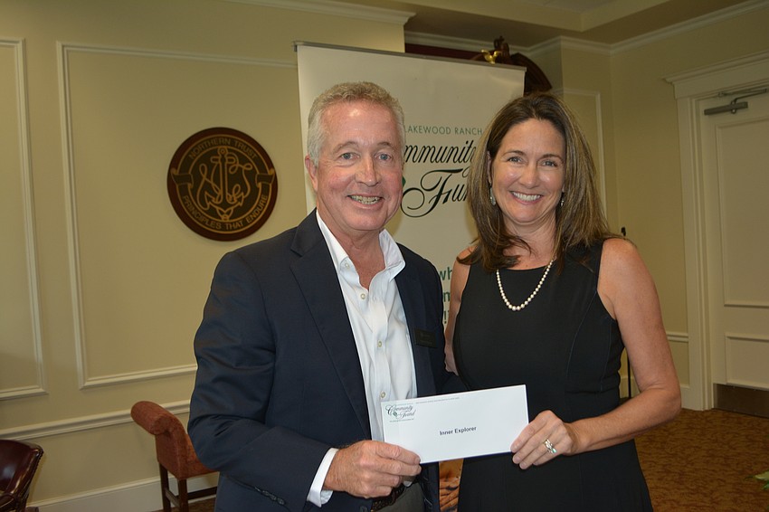 Kreg Hickman, GE’s regional manager, presents a check for $1,750 to Inner Explorer's Laura Bakosh.