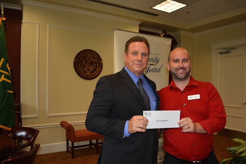 Community Foundation President Chris Romine presents a check for $4,500 for We Care Manatee's Kyle Blood.