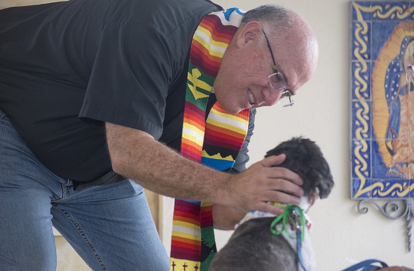 Pastor Wayne Farrell blesses Walter the dog during St. Boniface's pet blessing.