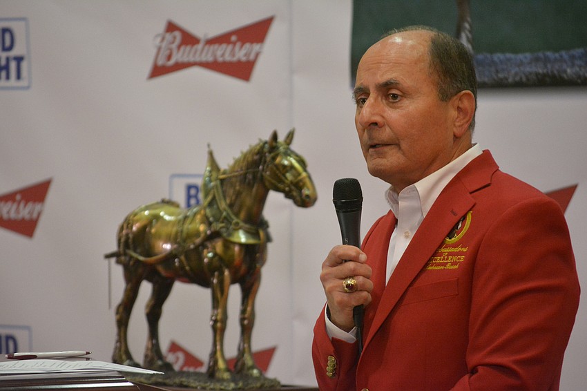 John Saputo, Gold Coast Eagle's owner and president, delivers an emotional message to his employees after accepting the Ambassadors of Excellence Big Jake (in background) statue.