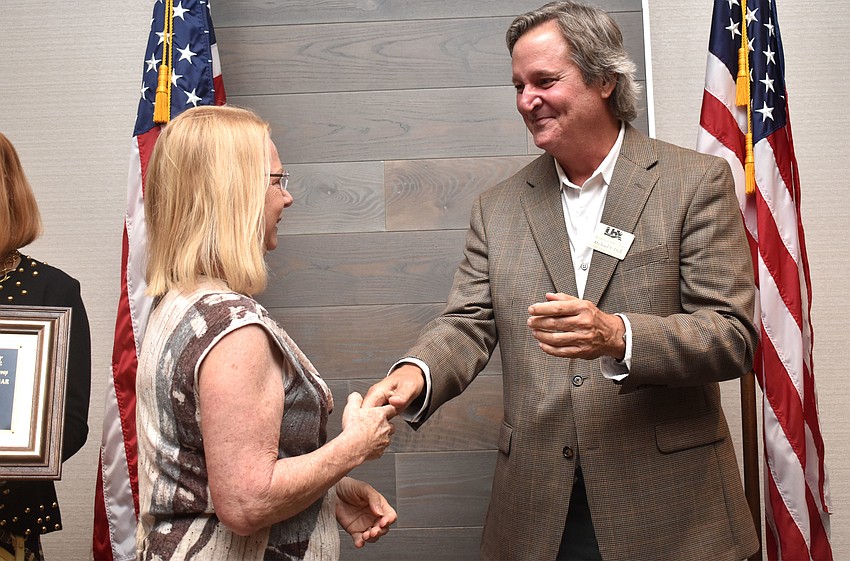 Chamber Chairman Michael Doll shakes hands with Karen Lapensee of LaPensee Plumbing, the winner of Small Businesspersons of the Year 11 to 100 employees