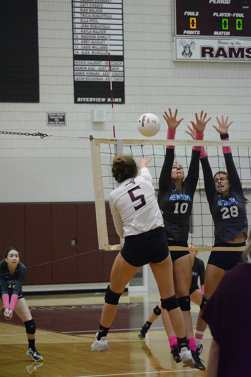 Riah Walker (5) slams a shot past leaping Newsome High blockers. Walker had 13 kills on the evening.