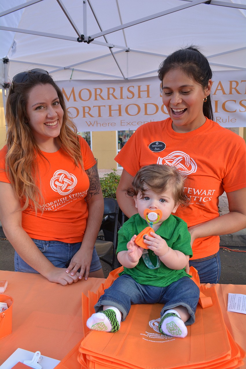 Nicole Keegan and Ines Olmos, employees at Morrish Stewart Orthodontics, got a little help working their booth from Lucas Kripas, son of co-worker Dana Bellew, not pictured.
