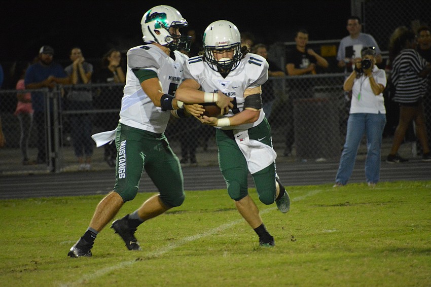 Mustangs quarterback Justin Curtis hands the ball to Mason Fischer.