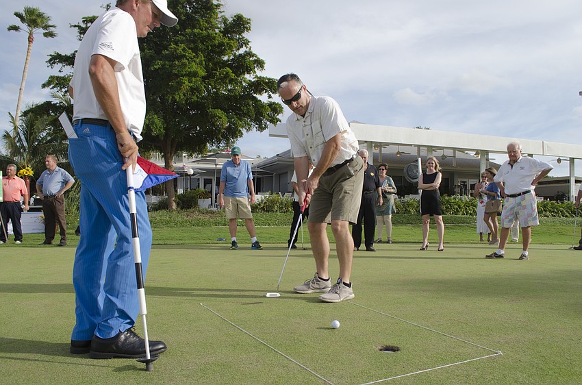 Fire Chief Paul Dezzi (right) raised $1,100 for Longboat Key's emergency services Saturday, sinking his first two shots in two strokes and the last in three.