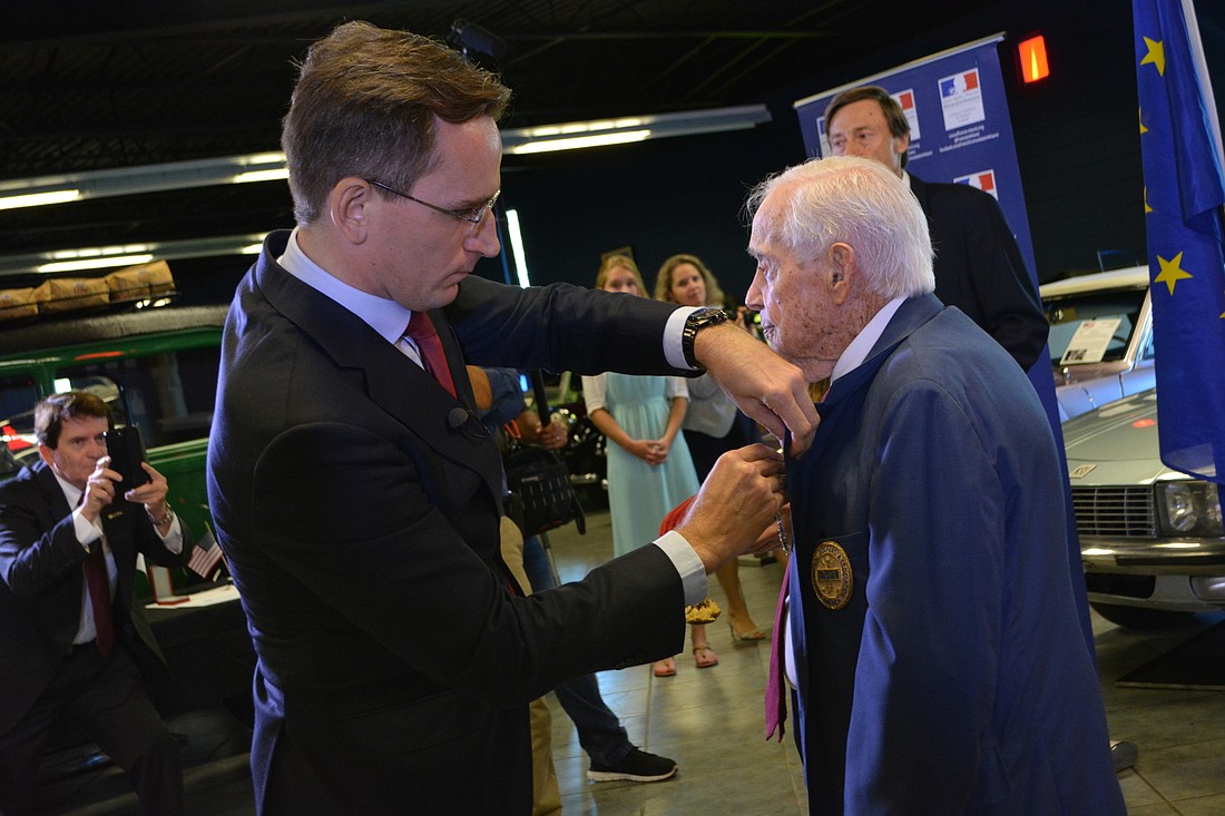 Consul General of France in Miami Clement Leclerc pins a medal on 106-year-old Gus Andreone.