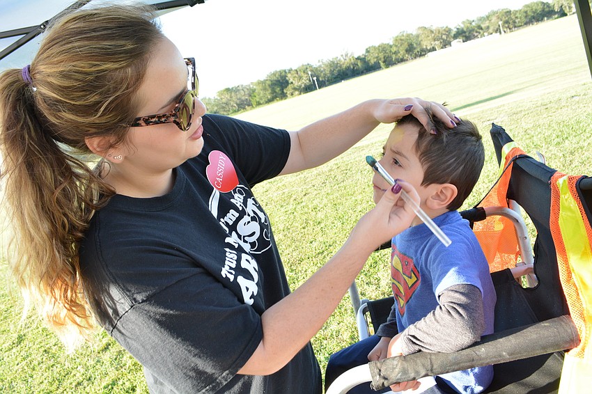 Artist Cassidy David paints the face of 4-year-old Braden Baker to match his Superman T-shirt while visits Tarrytown before the show.