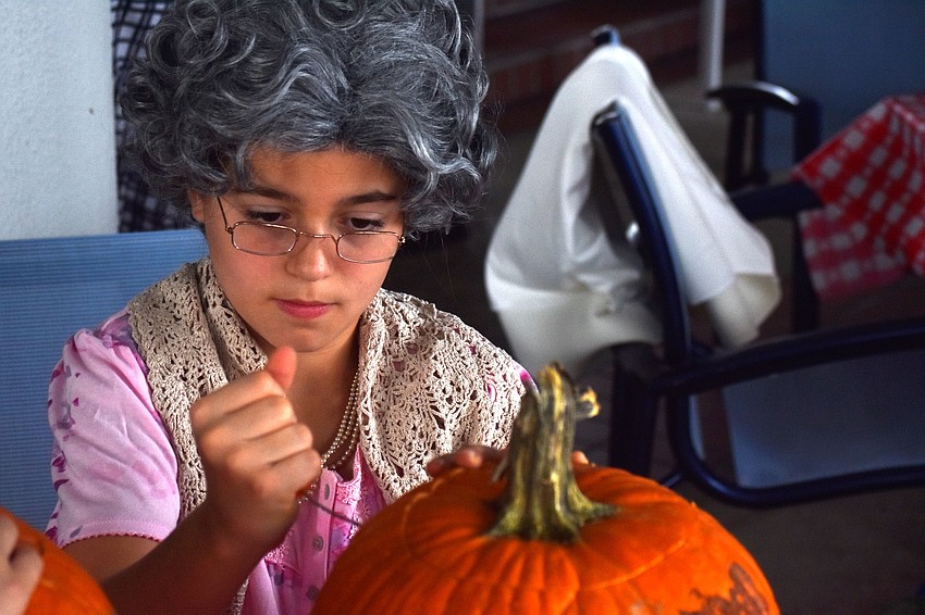Emma Martin carves into her pumpkin.
