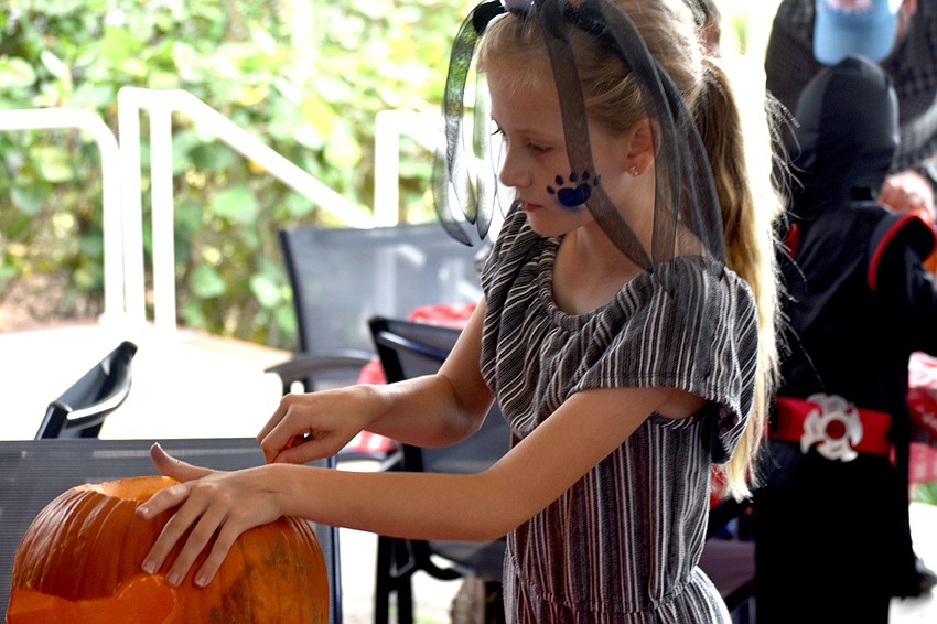 Madeleine Conger begins carving her pumpkin.
