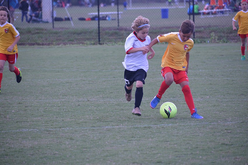 Lakewood Ranch U9 player Lucas Diaz fends off a Ives Estates player.