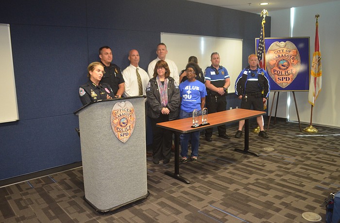 SPD Chief Bernadette DiPino (behind podium) speaks alongside volunteers and members of the department's Homeless Outreach Team during a press conference announcing the IACP awards.