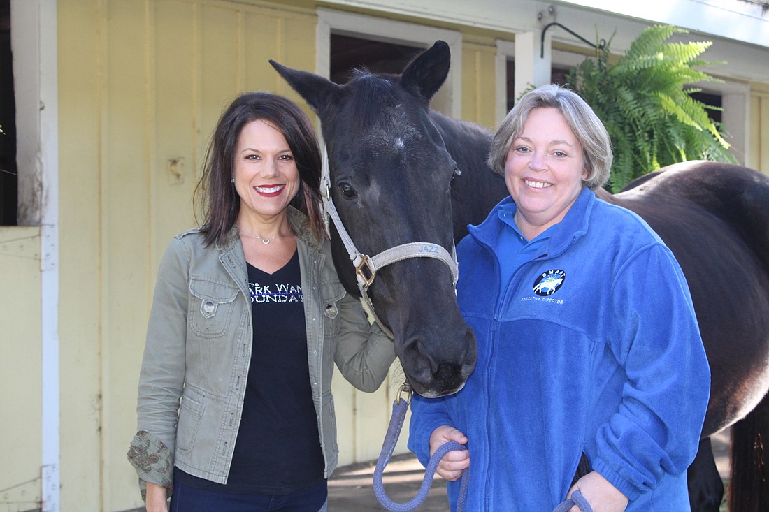 Melissa Wandall, founder of the Mark Wandall Foundation, and Brandi Ezell, executive director at Sarasota Manatee Association for Riding Therapy, celebrate their partnership with Jazz, a therapy horse at SMART.