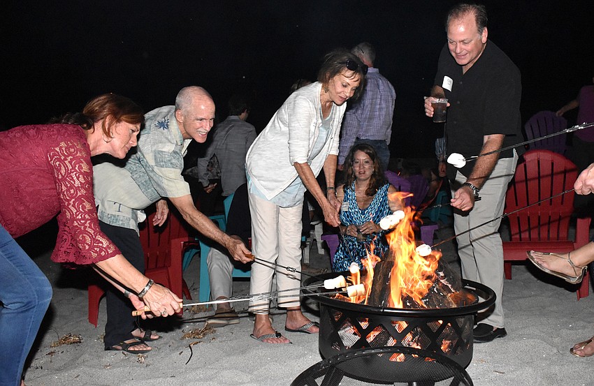 Doreen Clyne, Peter and Joanne Powers and Craig Tuley roast marshmallows on the beach for dessert.
