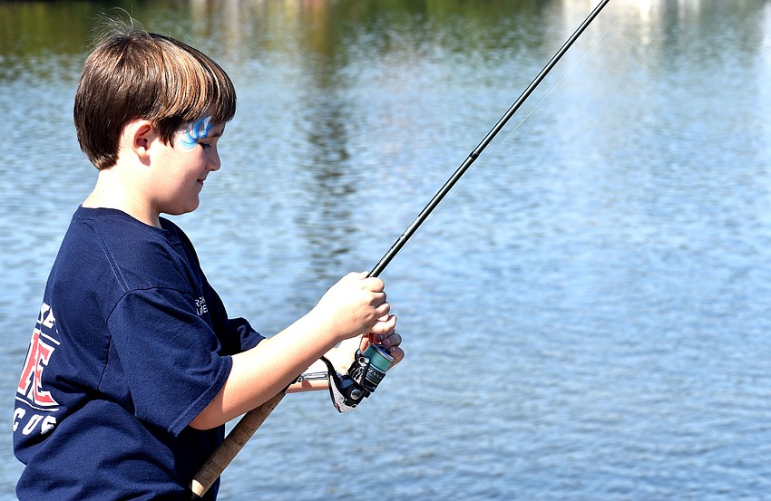 Jackson Kennedy tests out a fishing pole during a lesson from Rusty Chinnis.