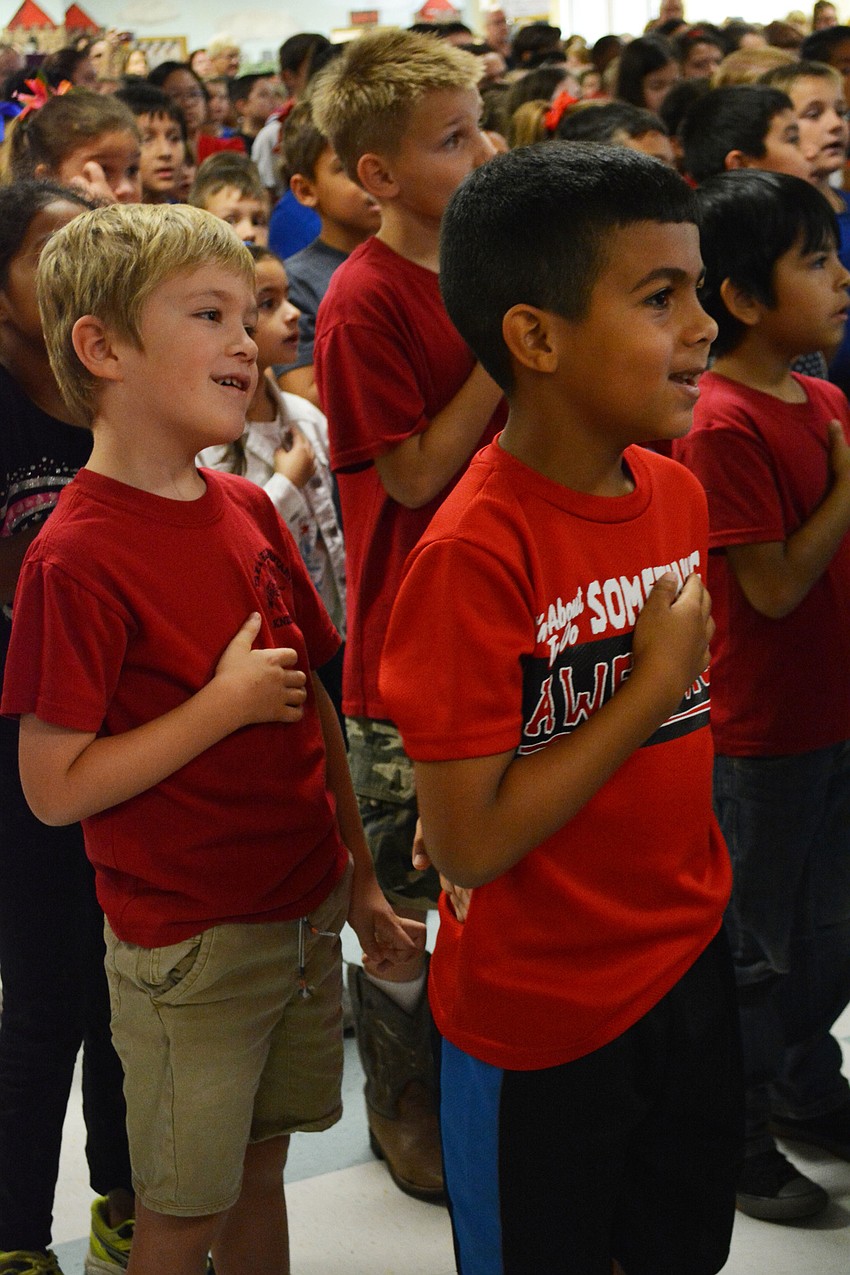 Samuel Wethers and Joseph Lopez, both first graders, stand for the Pledge of Allegiance at the start of the show.