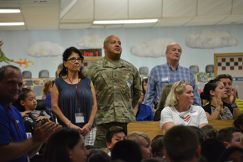 Tara staff member Maria Rodriguez and parent Sgt. 1st Class Alberto Corchado stand as students recognize veterans and military servicemen in the audience.