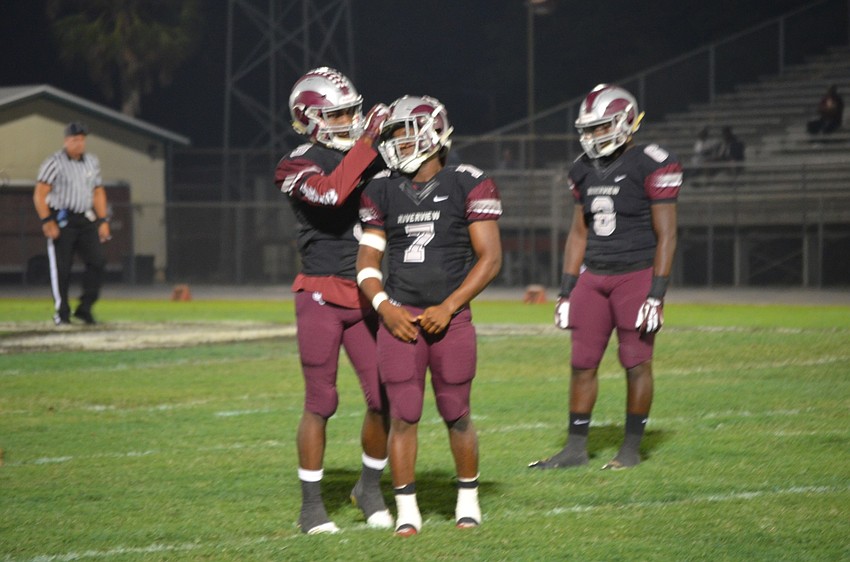 Julian Lowenstein (No. 9) gives teammate Antrone Thomas (No. 7) a pat on the helmet after another defensive stop for the Rams.