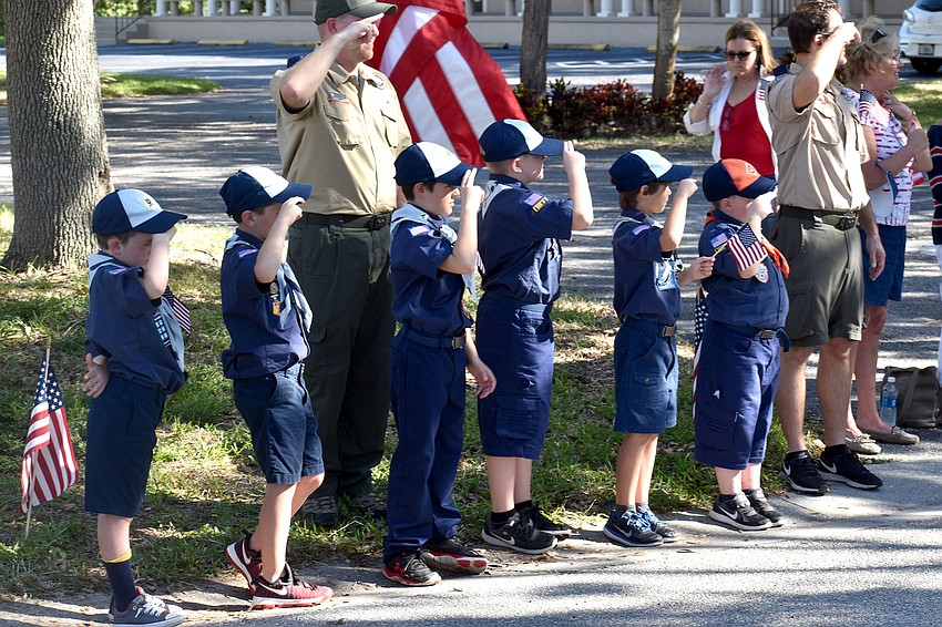 Boy Scouts salute veterans as they pass them on the parade route.