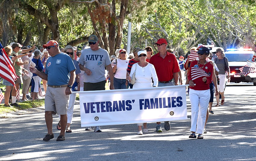 Veteran’s families wave to the crowd as they walk the parade route.