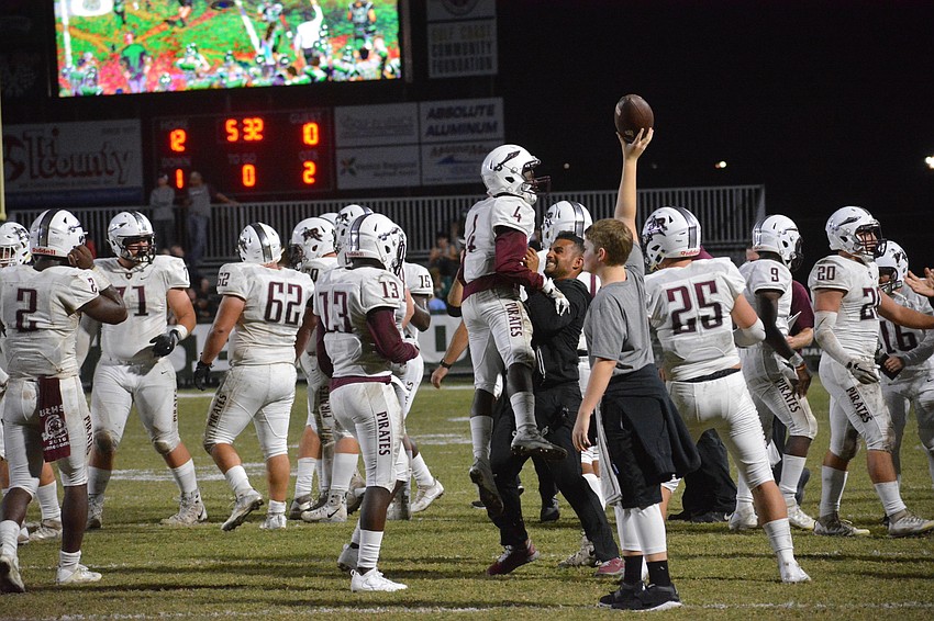 Sophomore defensive back Jameire Hayes (4) is hoisted by Pirates coach Curt Bradley after Hayes recovered an onside kick in the second quarter.