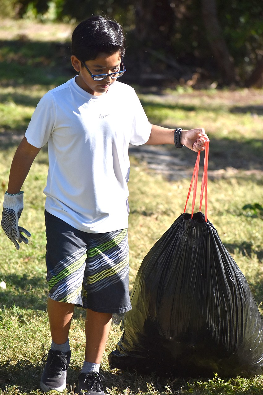 Max Ramos carries a trash bag during a cleanup on Quick Point Preserve.