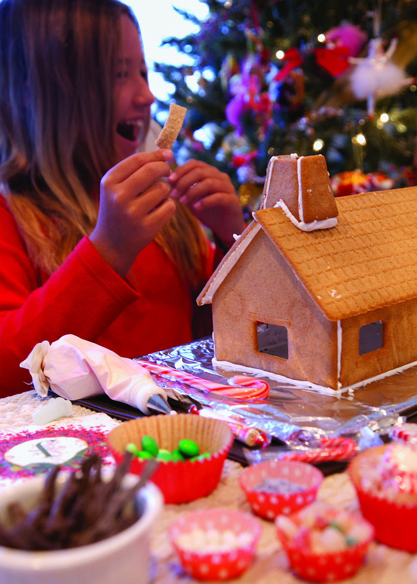 Julie Deffense's niece Madalena Deffense decorates a gingerbread house.