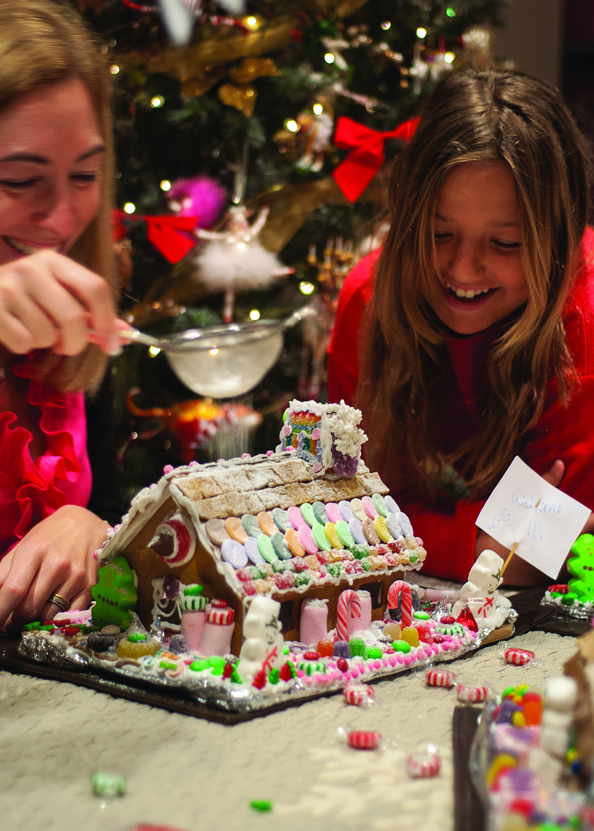 Julie Deffense and her niece Madalena Deffense decorate a gingerbread house.