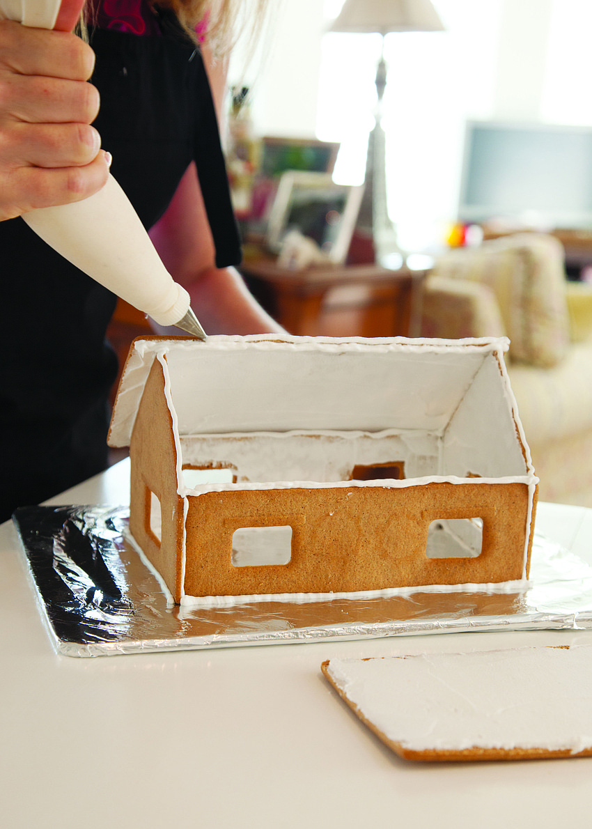 Julie Deffense recommends letting the icing holding the walls of your gingerbread house together to dry completely before adding the roof. Let that dry before beginning to decorate the house itself.