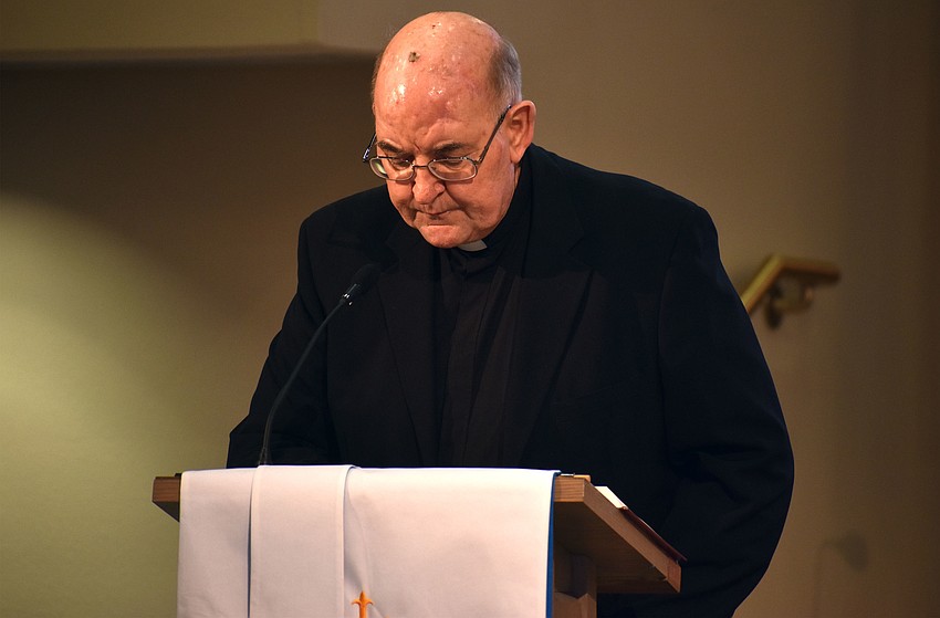 Monsignor Gerry Finegan of St. Mary, Star of the Sea, Catholic Church reads the scripture during the interfaith service.